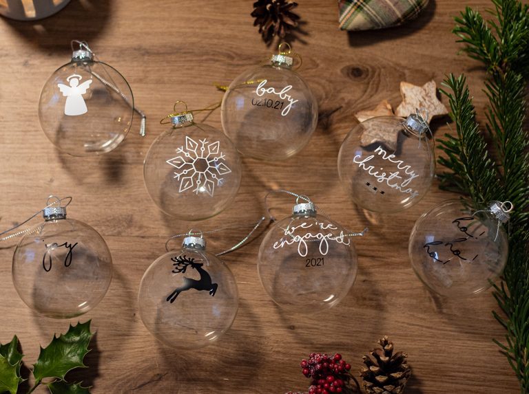 Palline di vetro natalizie come decorazione realizzata in modo personalizzato con simboli e scritte create con la pellicola adesiva d-c-fix® bianca e nera.