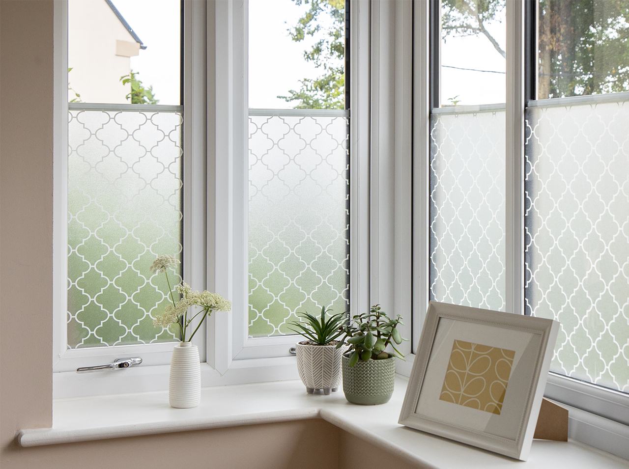 Window covered with milky opaque window foil with oriental outline pattern in white