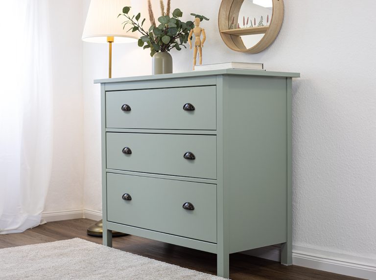 A chest of drawers finished in bright soft green foil stands against a wall in a kids’ room.