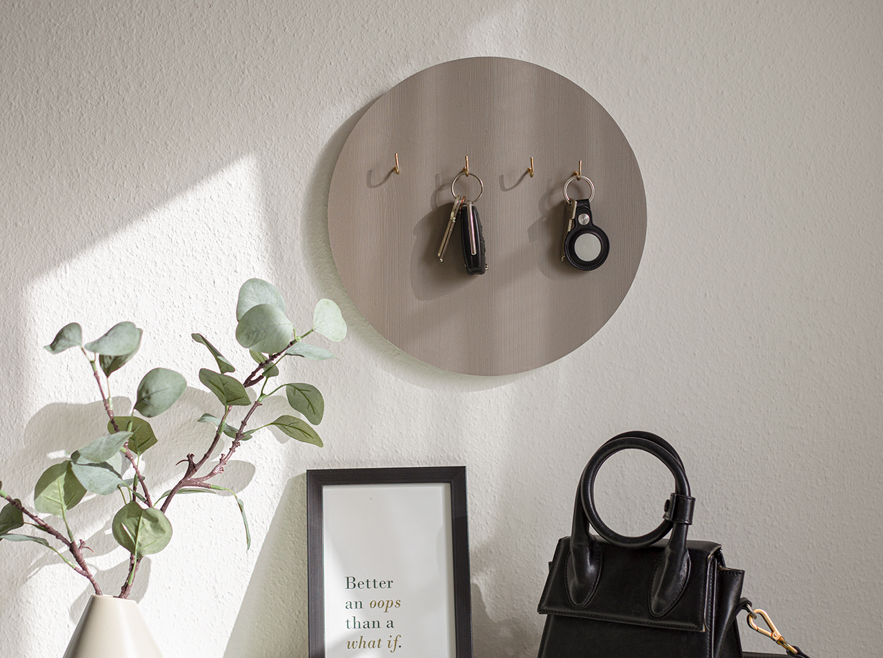 Round rack covered with foil in grey wood look with several gold-colored hooks to hang your keys on.