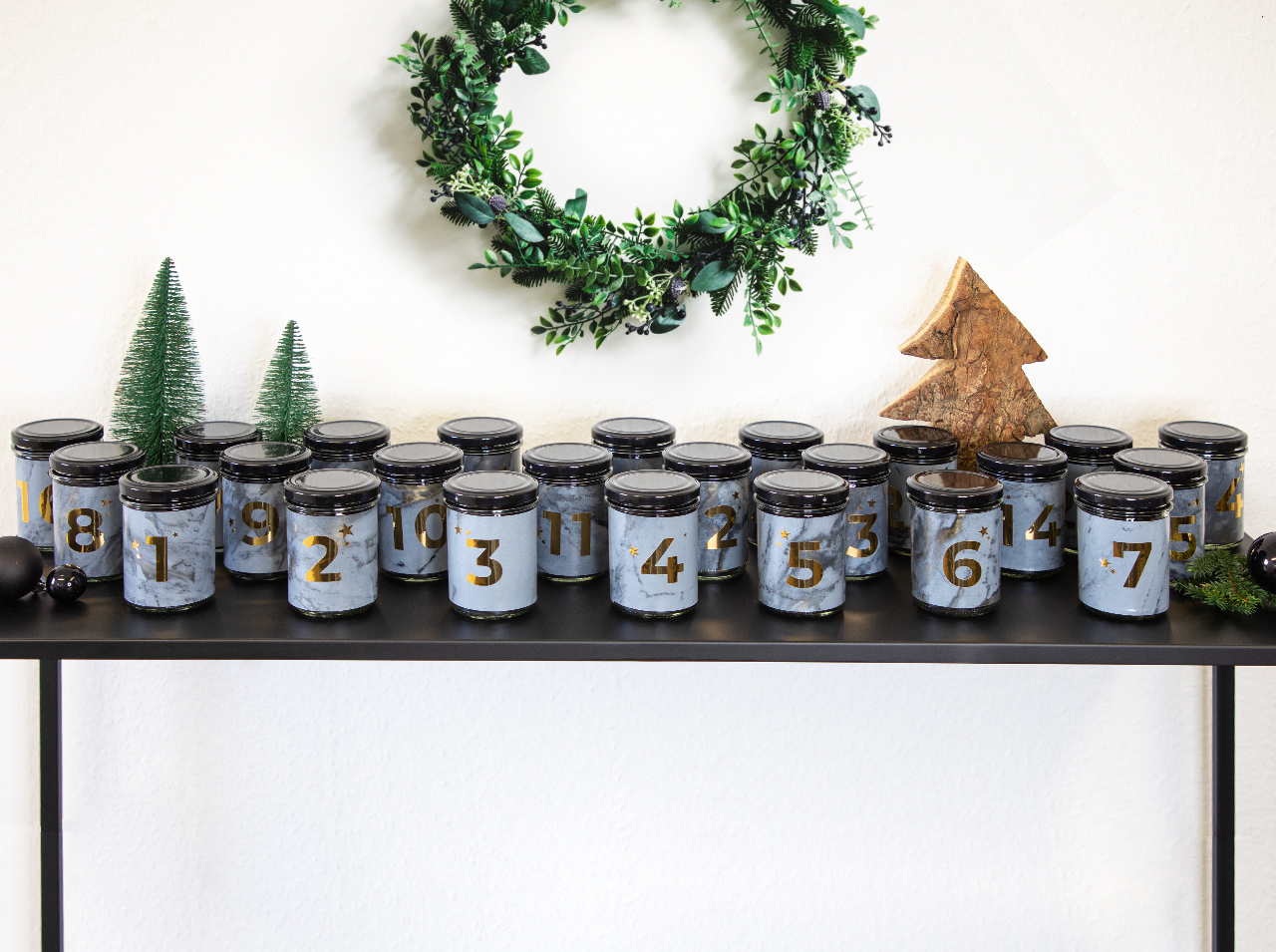 Different size screw-top jars in a dark marble look with applied gold stars and numbers.