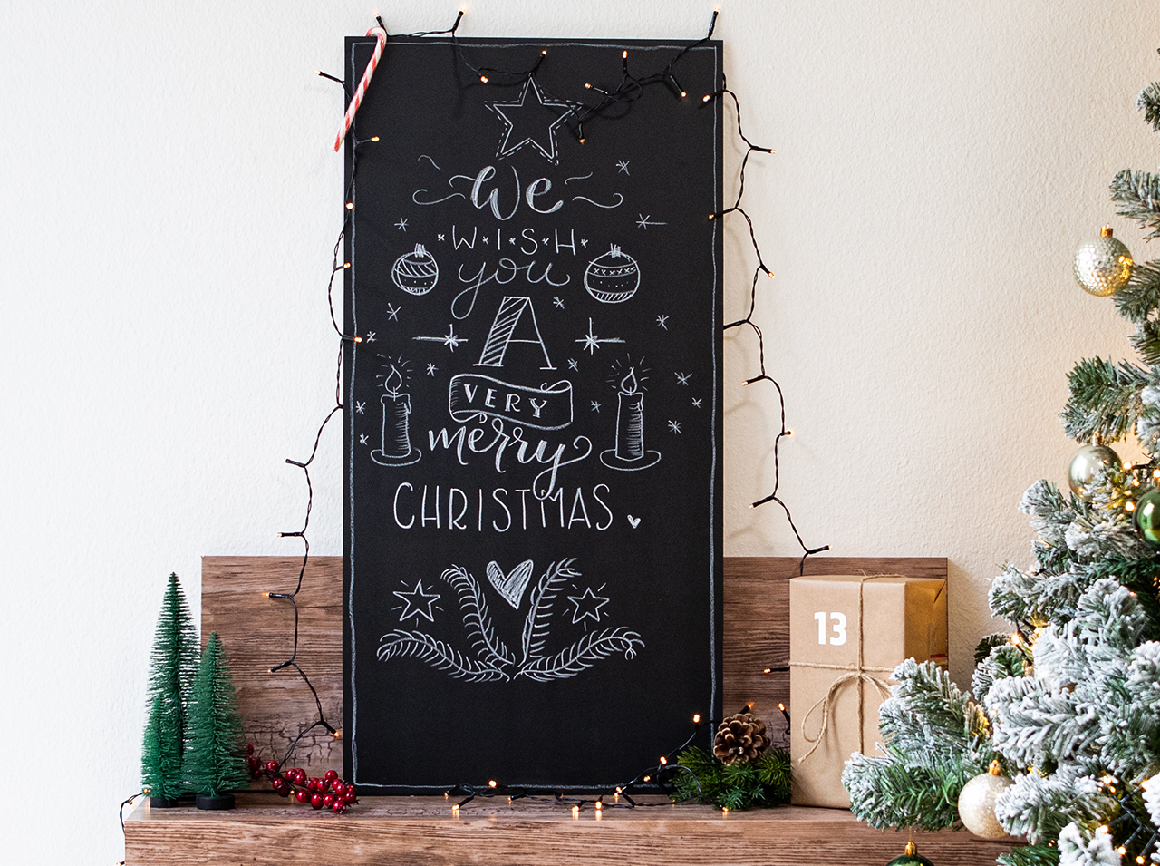 Grand plaque recouverte d’un film pour tableau noir, inscrite et peinte au crayon craie sur le thème de Noël.