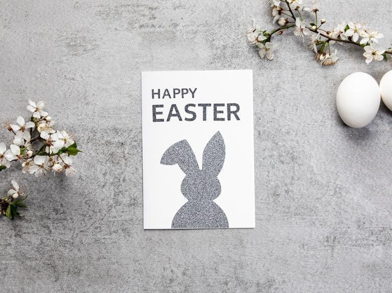 Faltkarte mit Hasen-Silhouette aus grauer Glitter-Klebefolie und Schriftzug „Frohe Ostern“ aus Glitter-Klebefolie in Anthrazit beklebt.