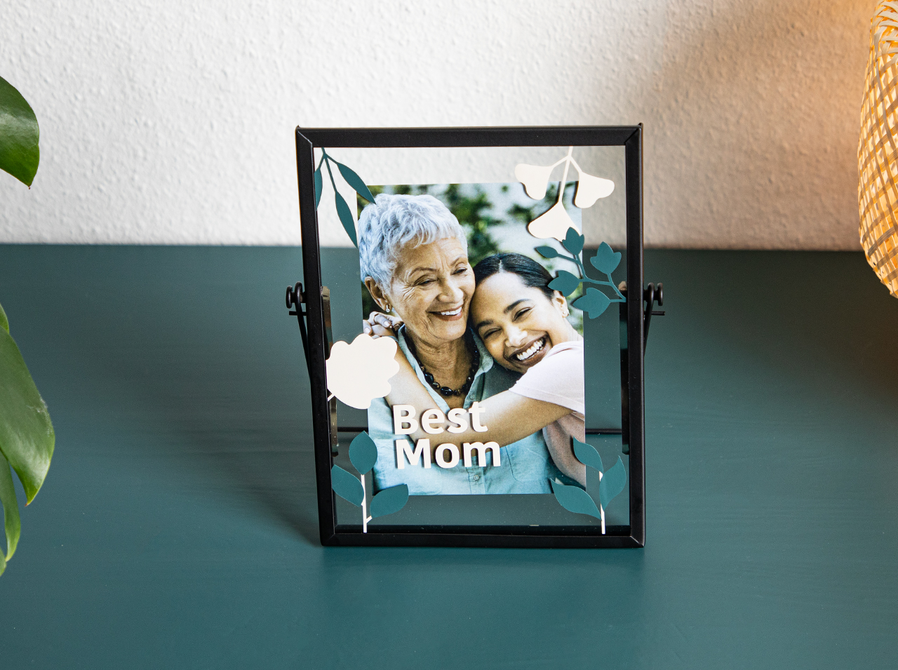 A transparent photo frame with a photo, decorated with flowers made from adhesive foil.
