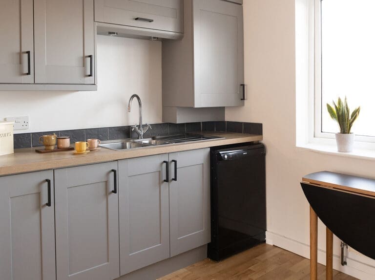 Кухонный гарнитур с серыми матовыми фасадами и прямоугольными черными ручками.