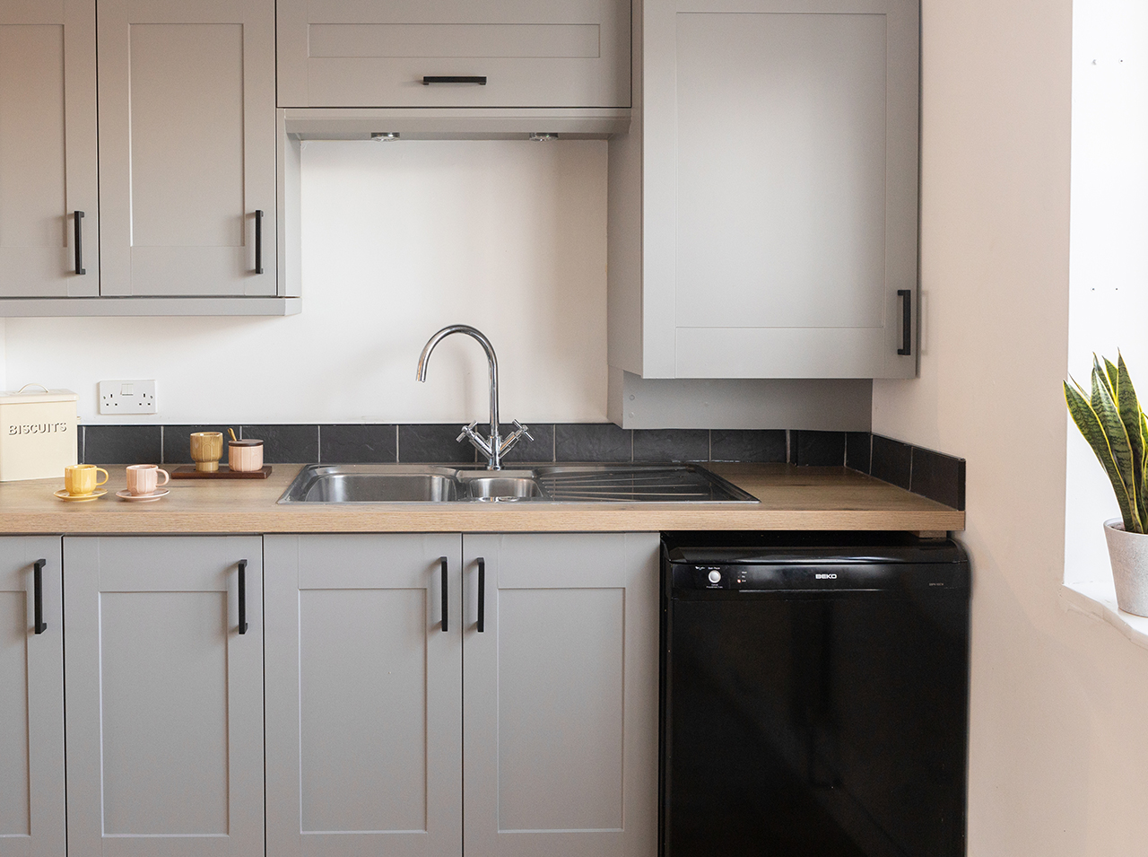 Кухонный гарнитур с серыми матовыми фасадами и прямоугольными черными ручками.