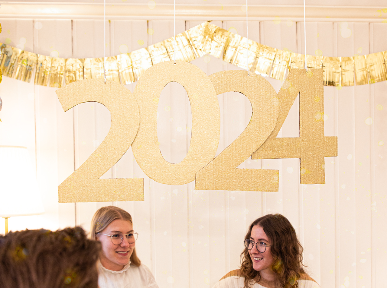 Jahreszahl 2024 als hängende Dekoration mit Ziffern in Glitter-Optik in Gold.