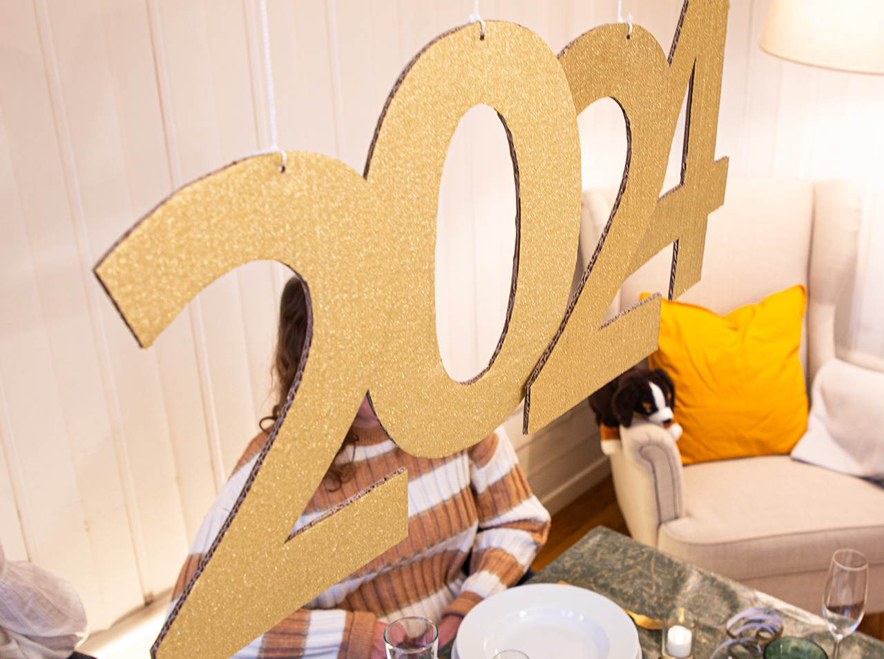Jahreszahl 2024 als hängende Dekoration mit Ziffern in Glitter-Optik in Gold.