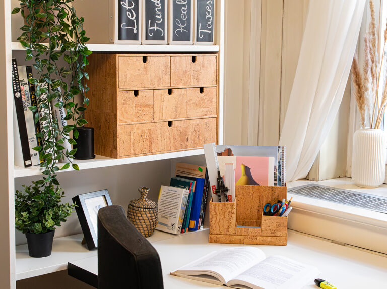 Bureau avec commode Ikea Moppe, porte-stylo, boîte pour bloc-notes et plateau de rangement aspect liège sur le dessus.